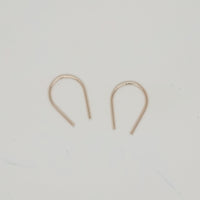 Gold U-shaped minimalist earrings displayed on white surface