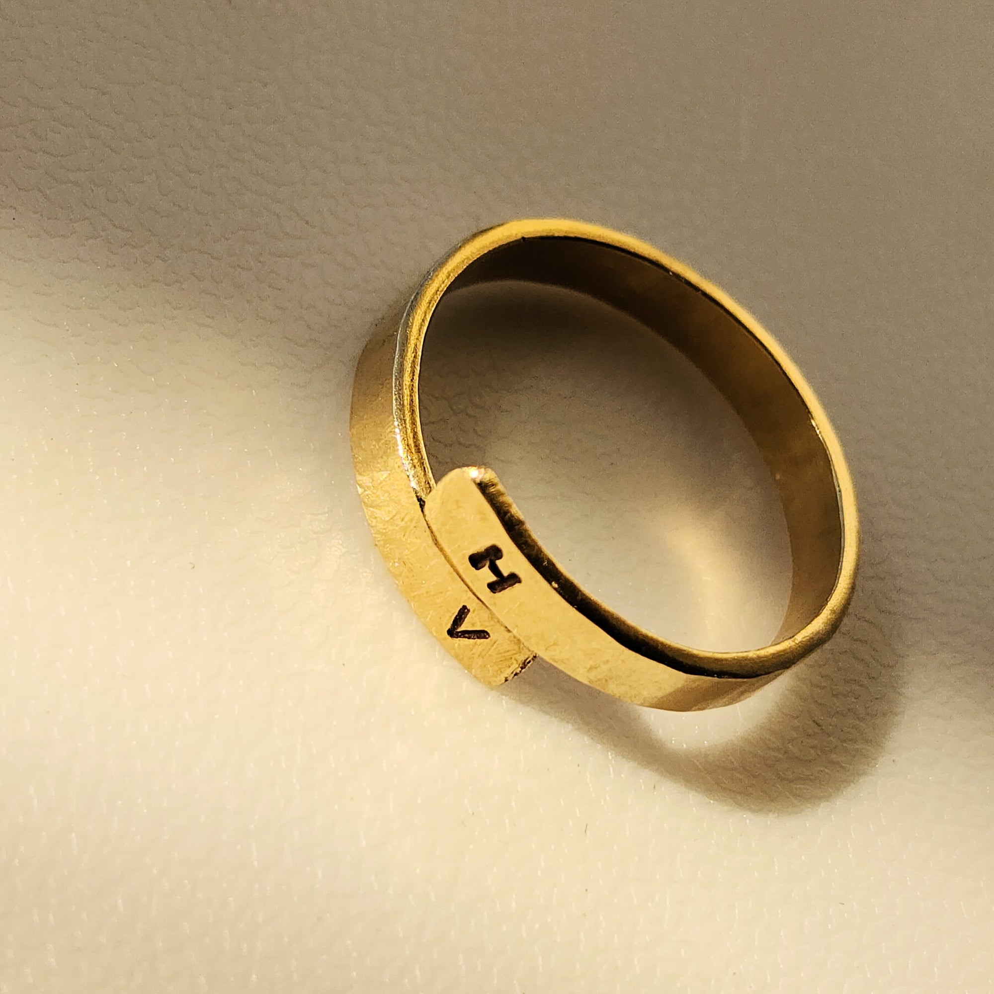 Gold ring with engraved initials on a beige background