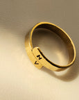 Gold ring with engraved initials on a beige background