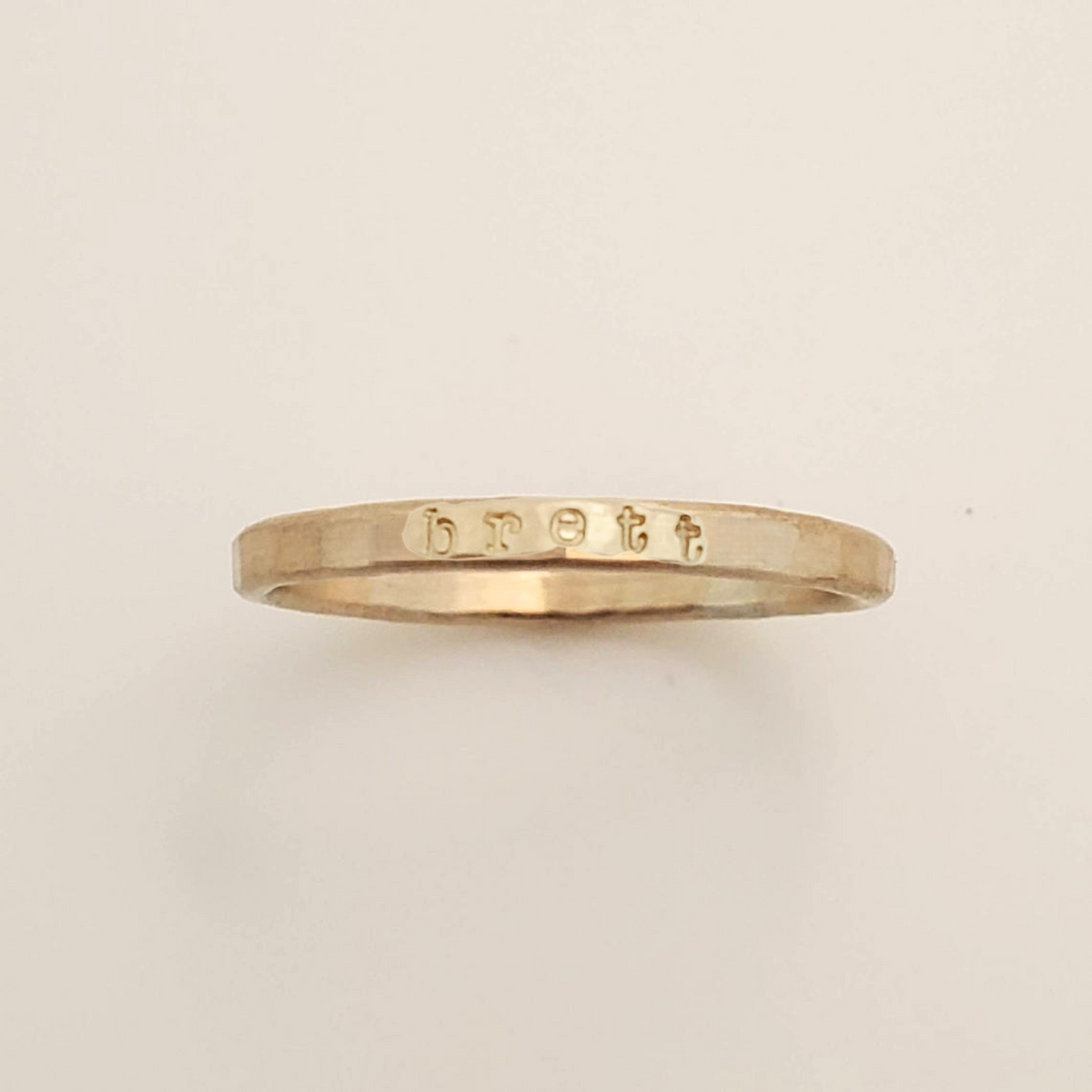 Gold ring with engraved text on a beige background