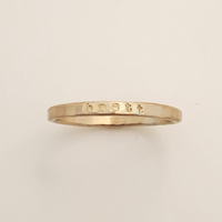 Gold ring with engraved text on a beige background