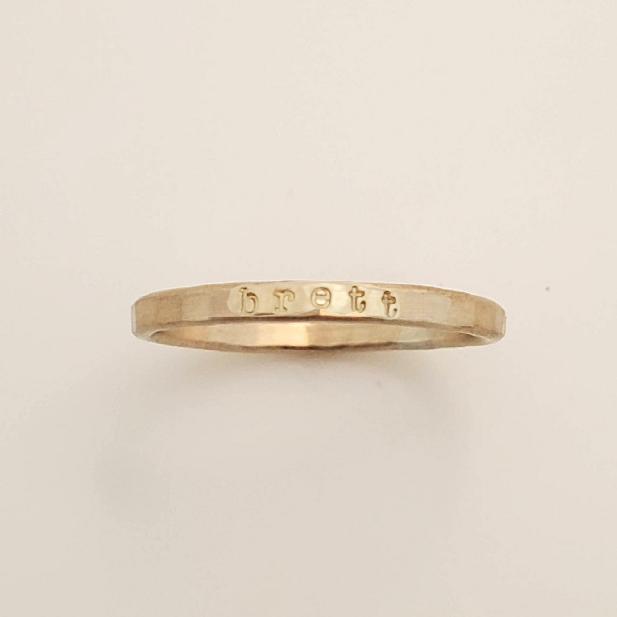 Gold ring with engraved text on a beige background