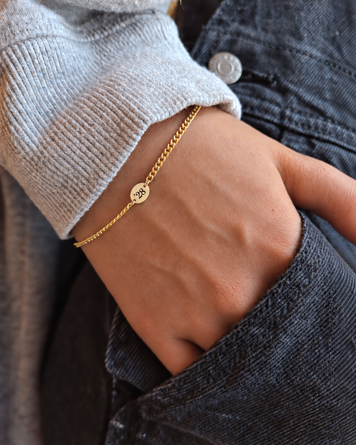 Gold '28 engraved bracelet in denim pocket