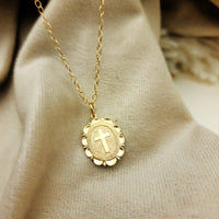 Gold necklace with a cross pendant on a beige fabric background