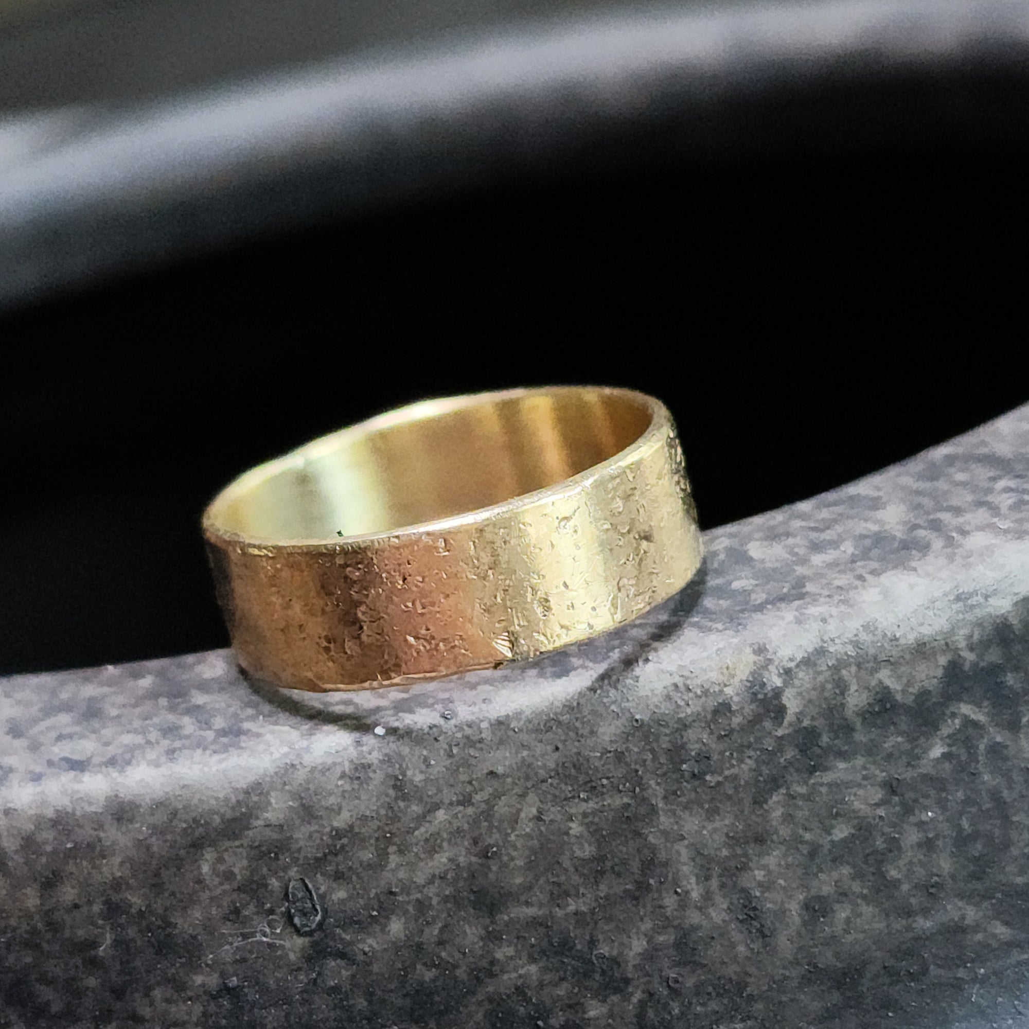 Gold ring on a dark stone surface
