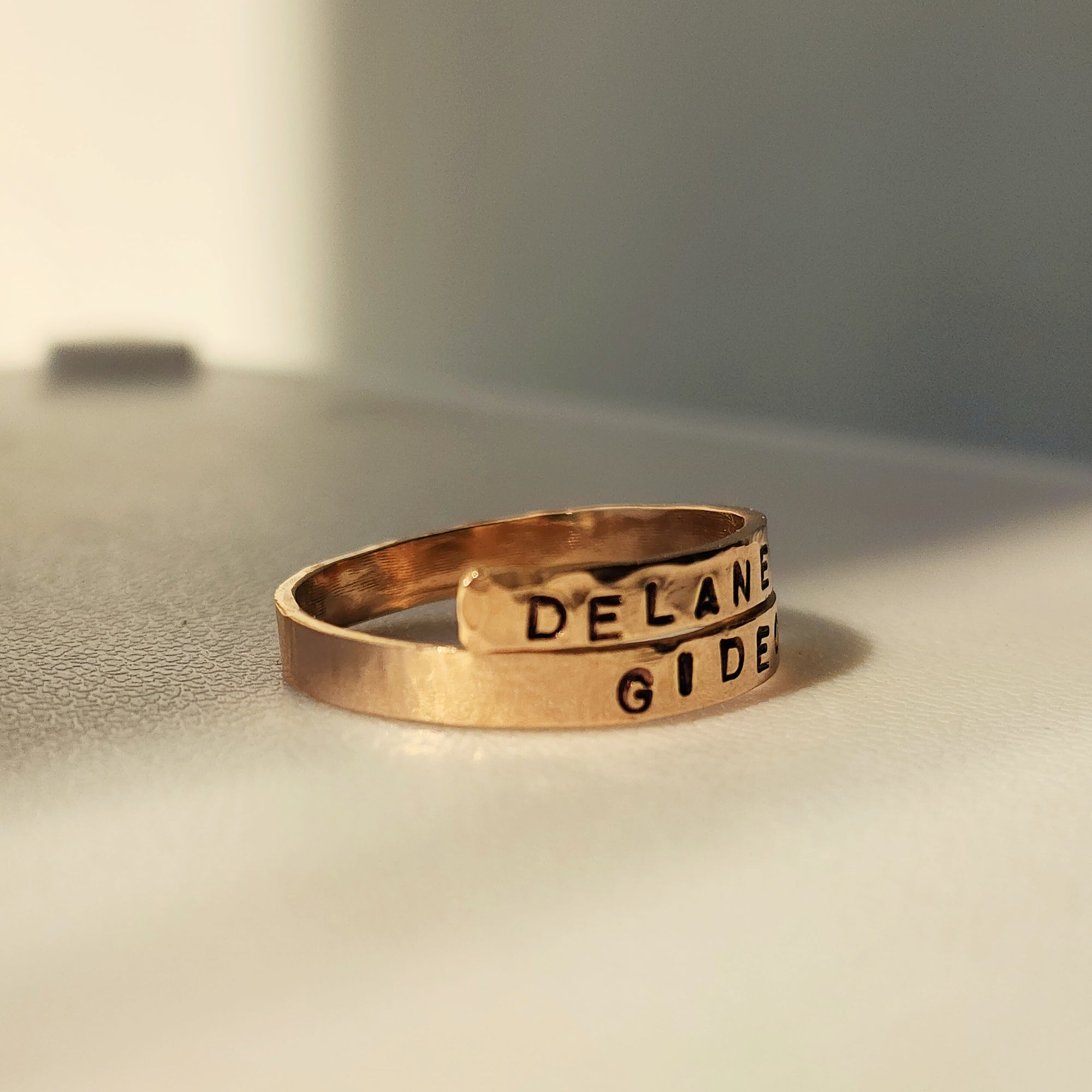 Gold ring with engraved text on a neutral background