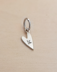 Silver heart-shaped pendant with a letter 'K' on a beige background