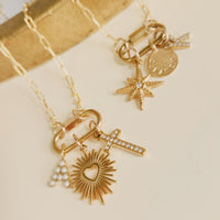 Gold necklace with various charms on a beige background