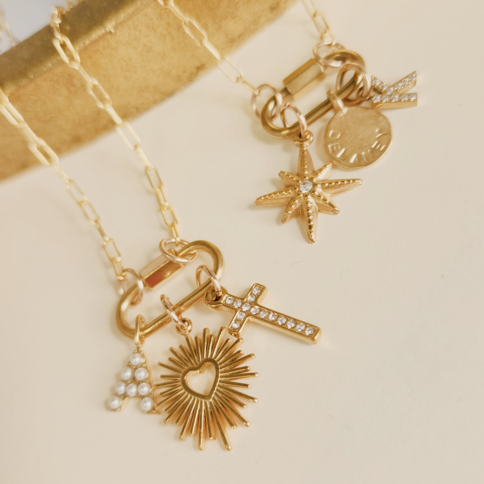 Gold necklace with various charms on a beige background