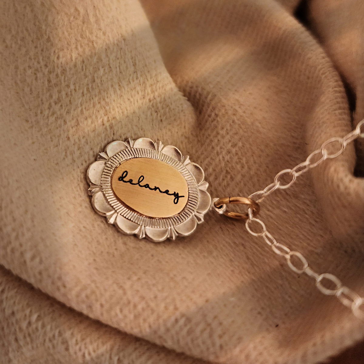 Gold necklace with a round pendant on a beige fabric background
