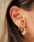 Gold U-shaped earrings stacked with other hoops on model’s ear