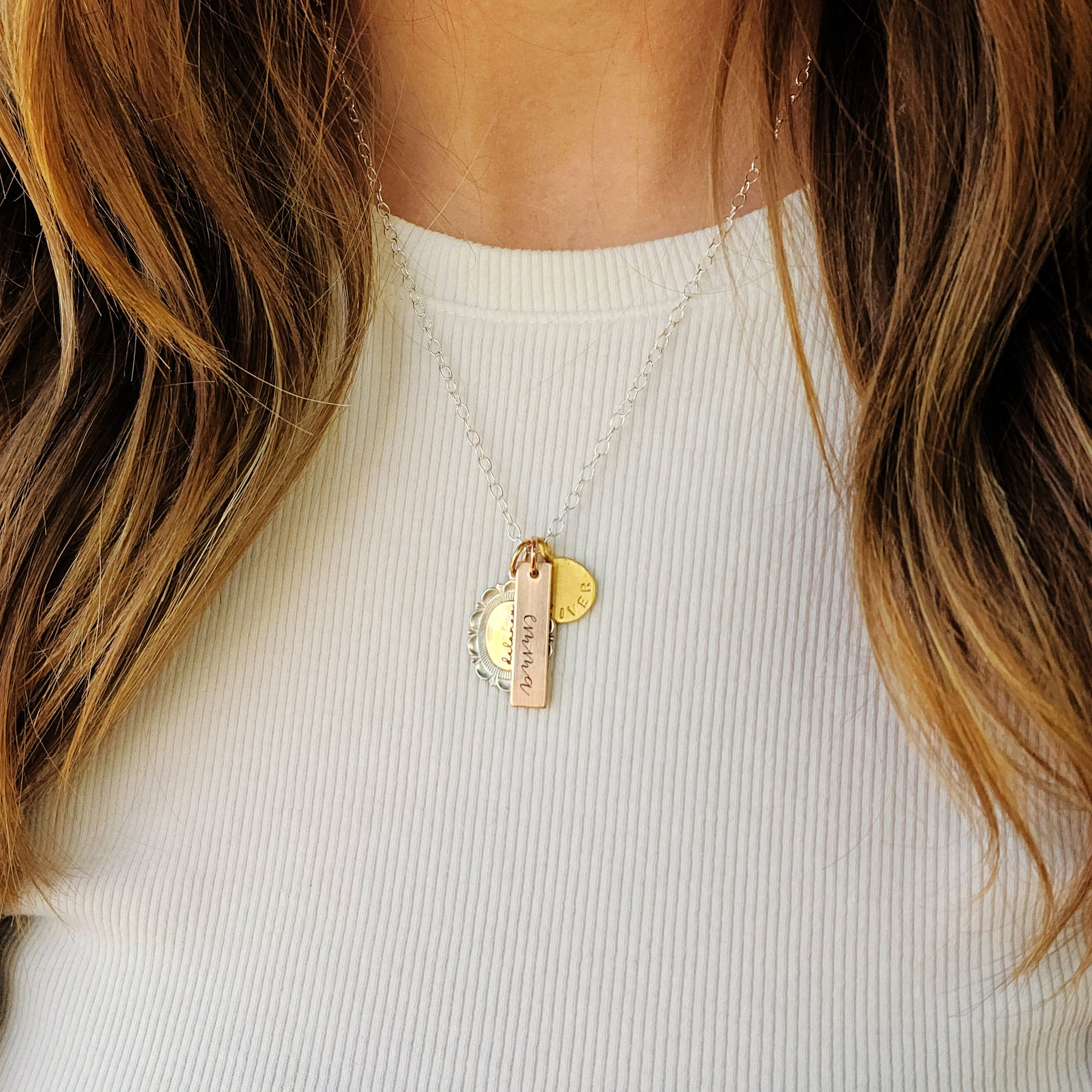Necklace with gold pendants worn by a person with long hair, against a white background