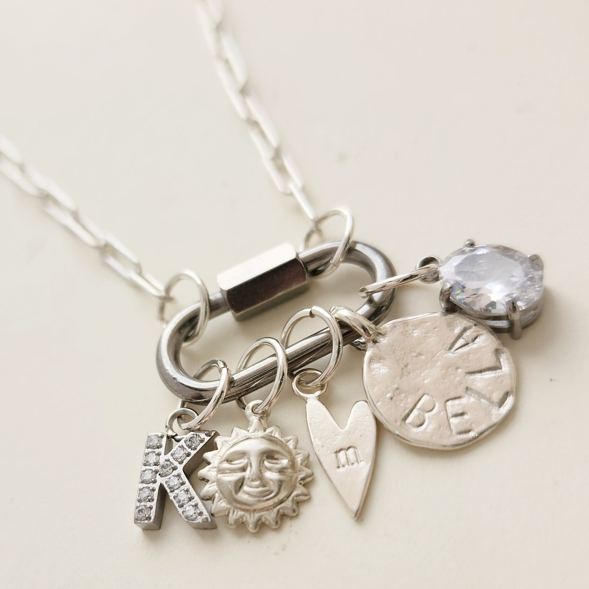 Silver necklace with various charms on a light background