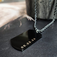 Black dog tag with gold text on a textured surface