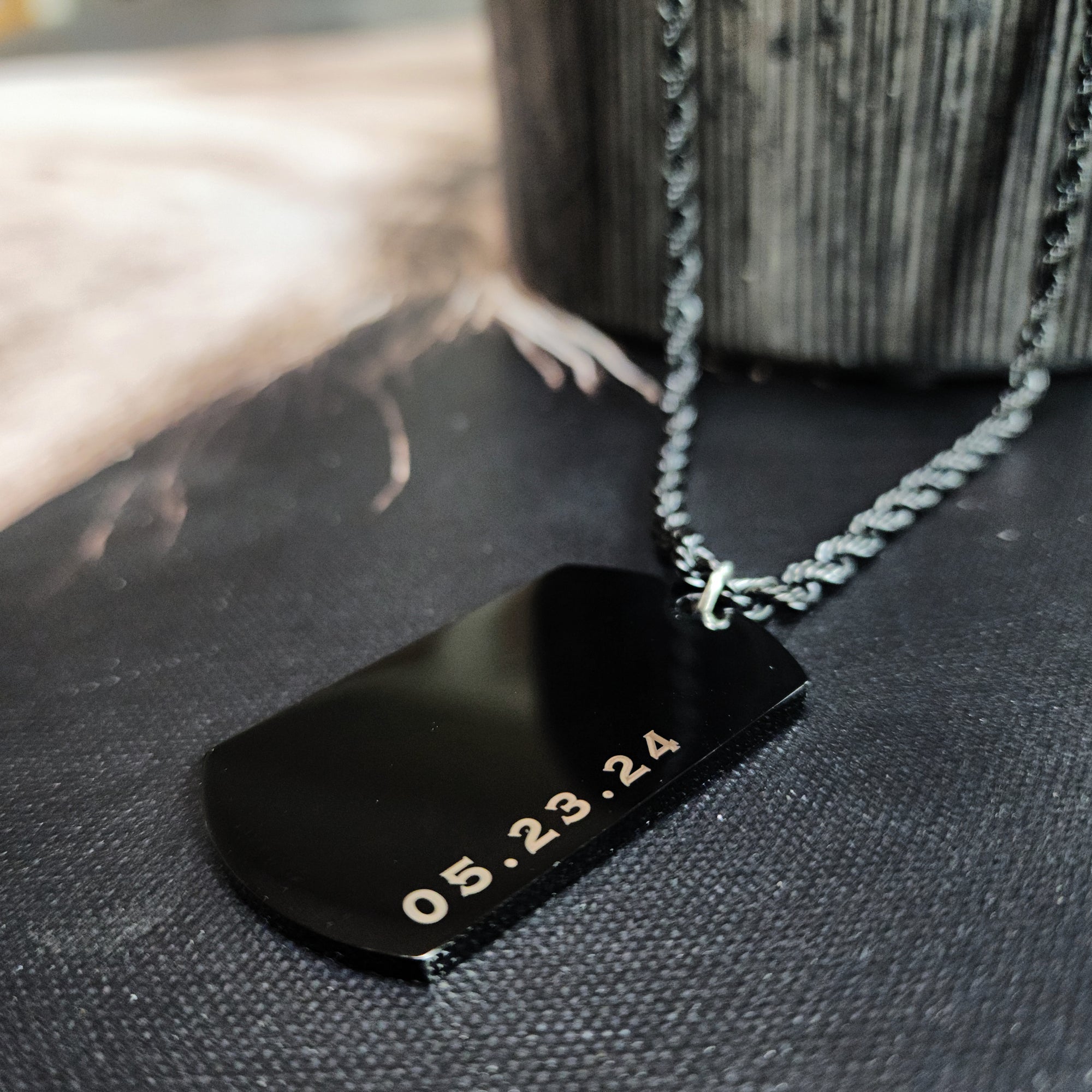 Black dog tag with gold text on a textured surface