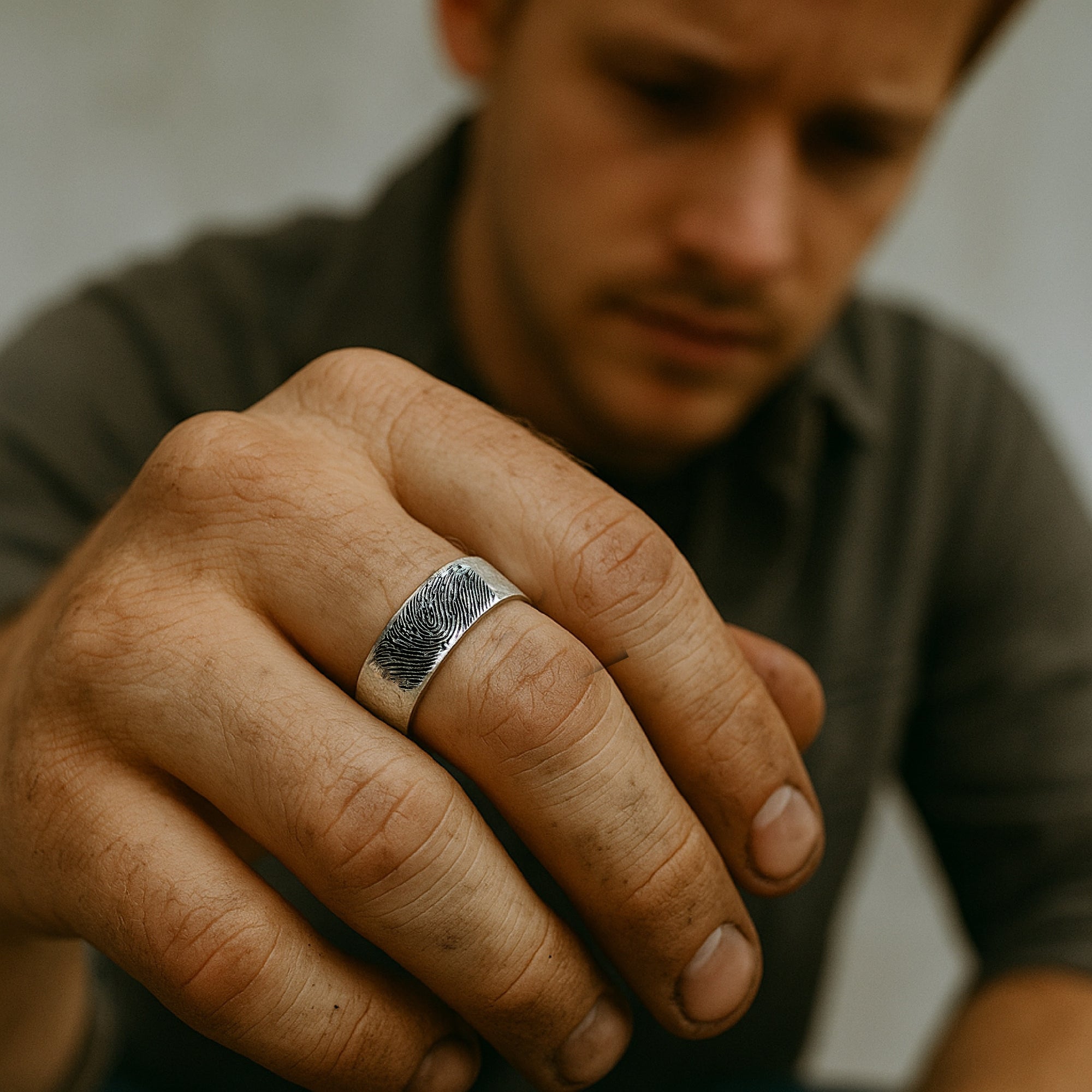 Man wearing a silver ring on his finger with a blurred background