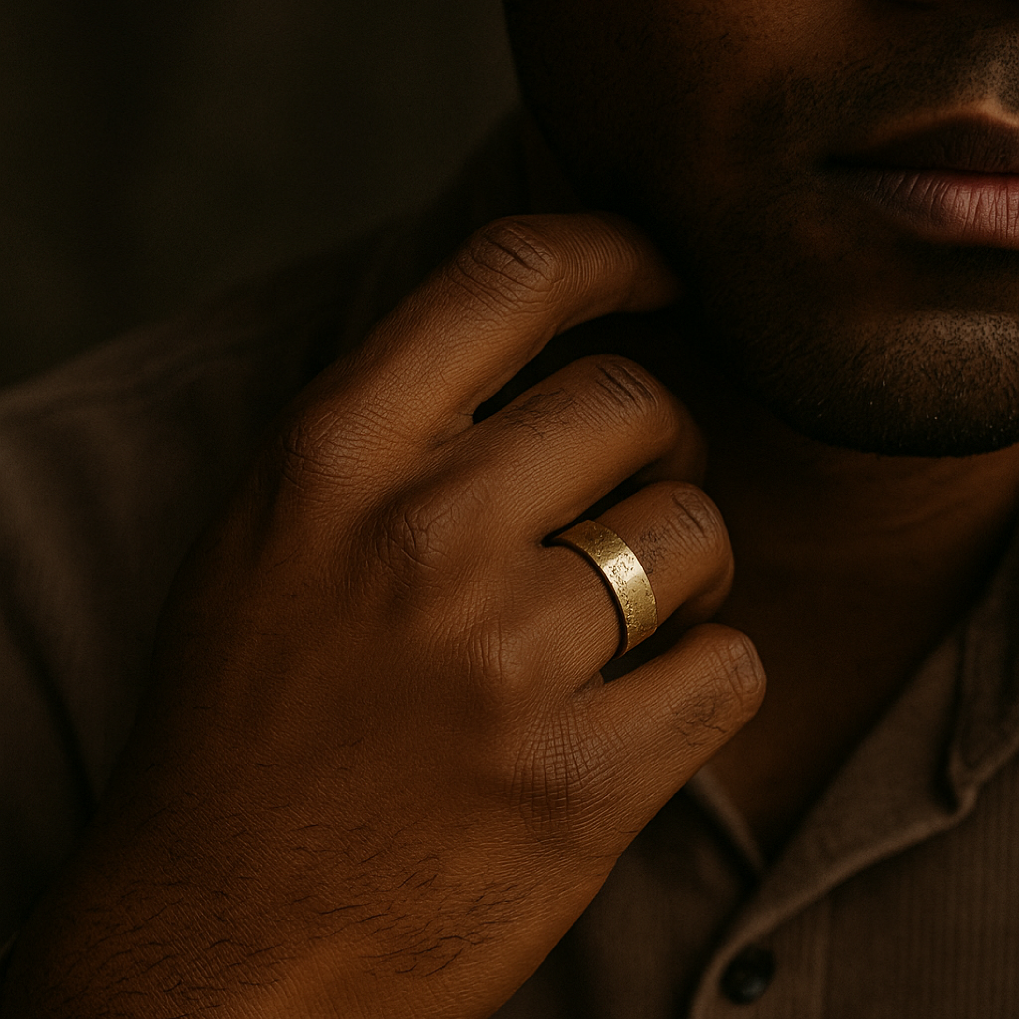 Close-up of a hand wearing a gold ring with a dark background