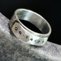 Silver ring with engraved date on a dark background