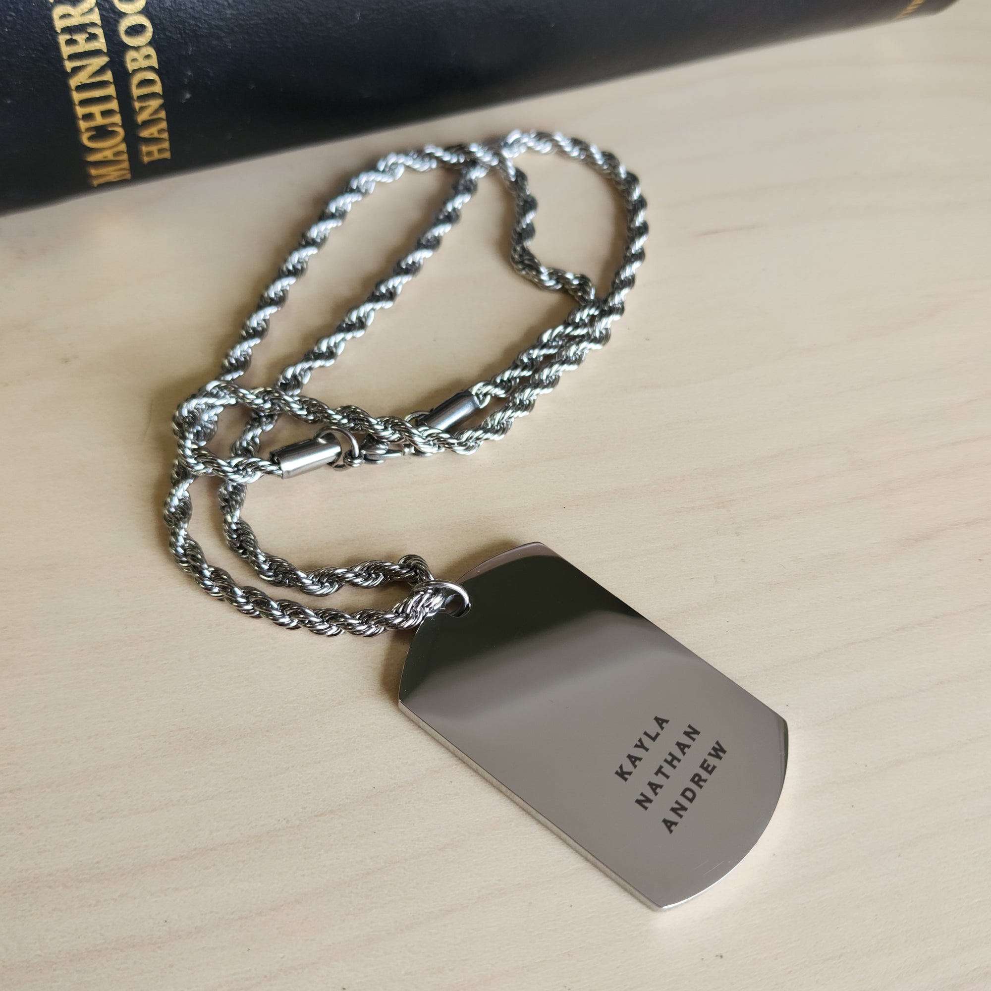 Metal dog tag with engraved text on a wooden surface