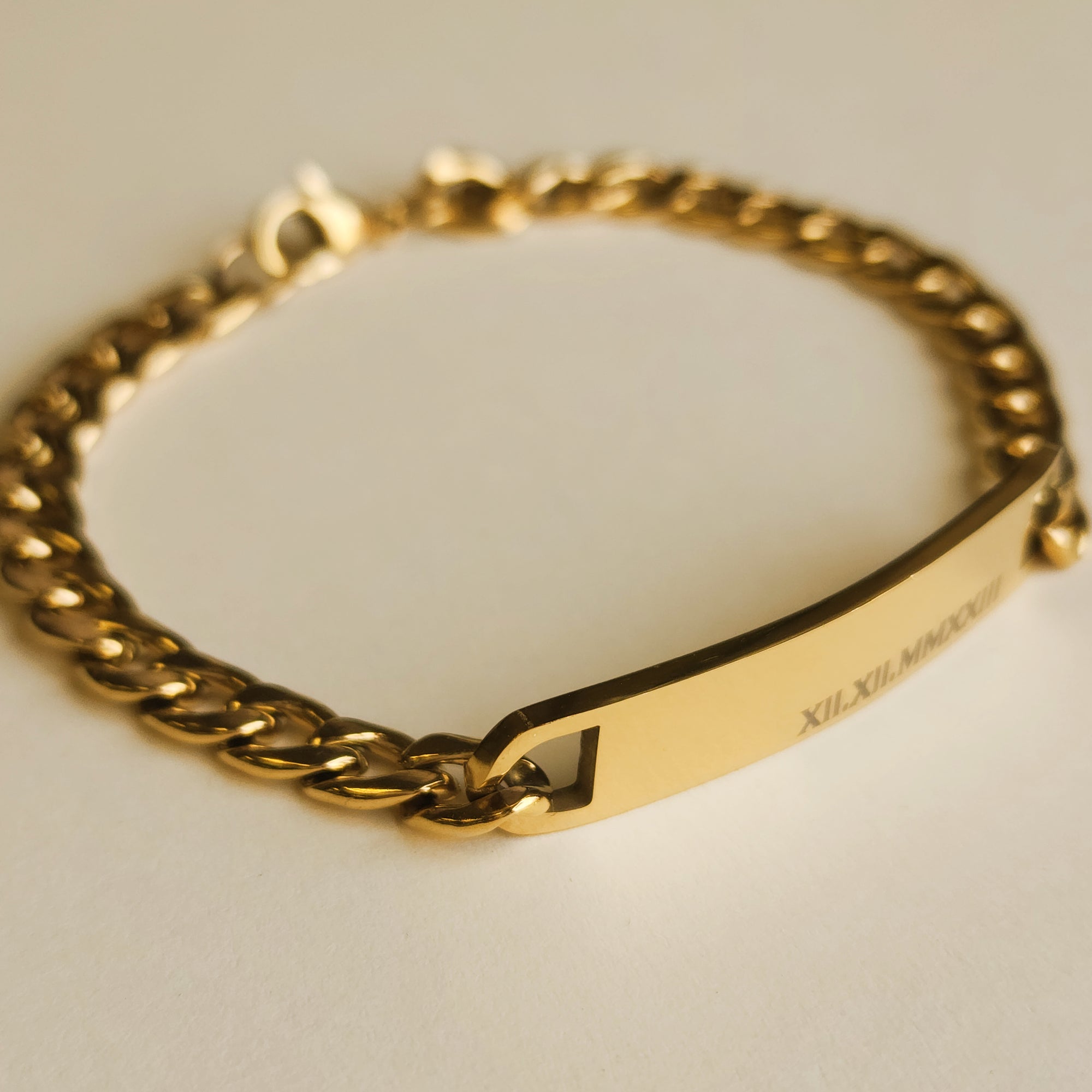 Gold chain bracelet with a nameplate on a light background