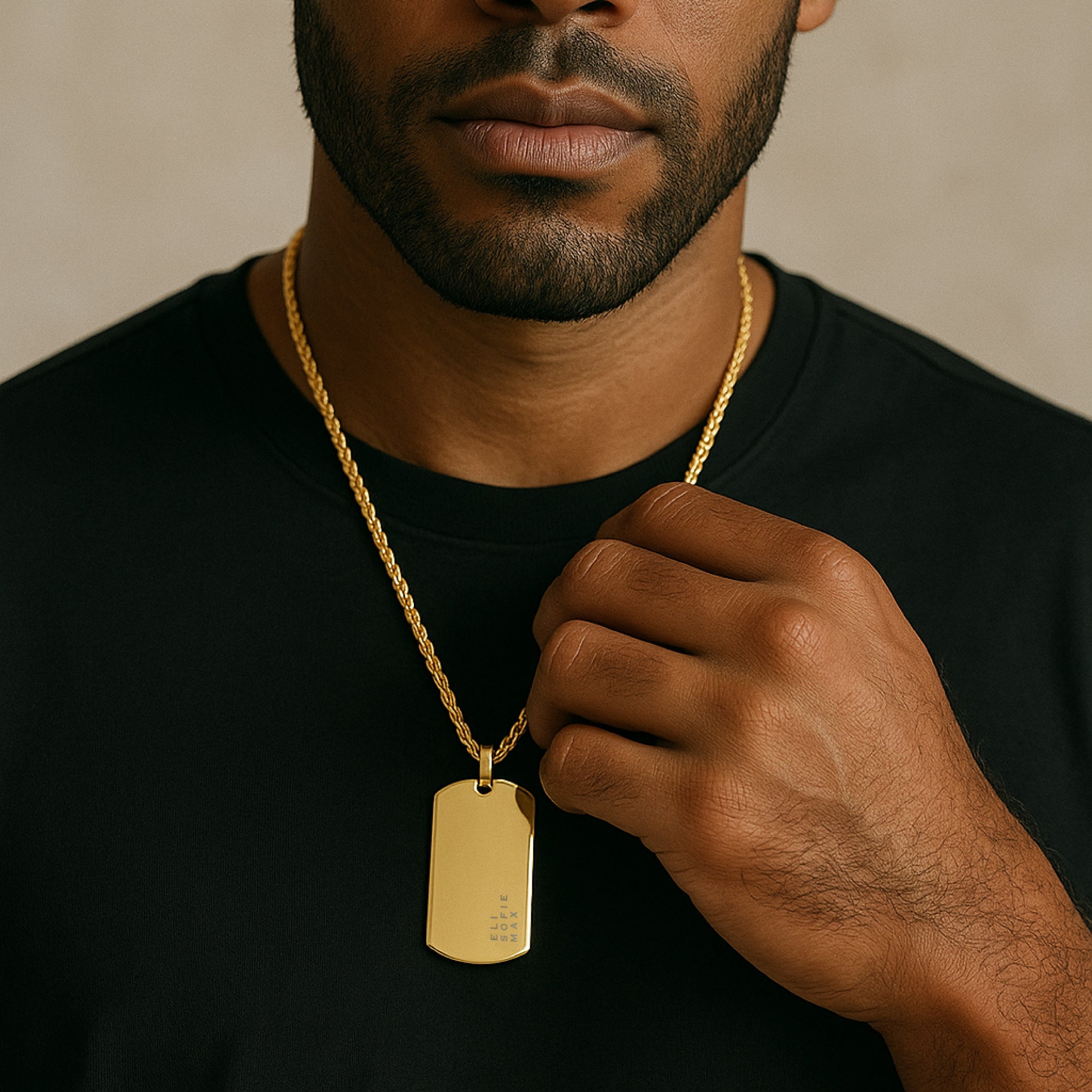 Man wearing a gold necklace with a dog tag against a neutral background
