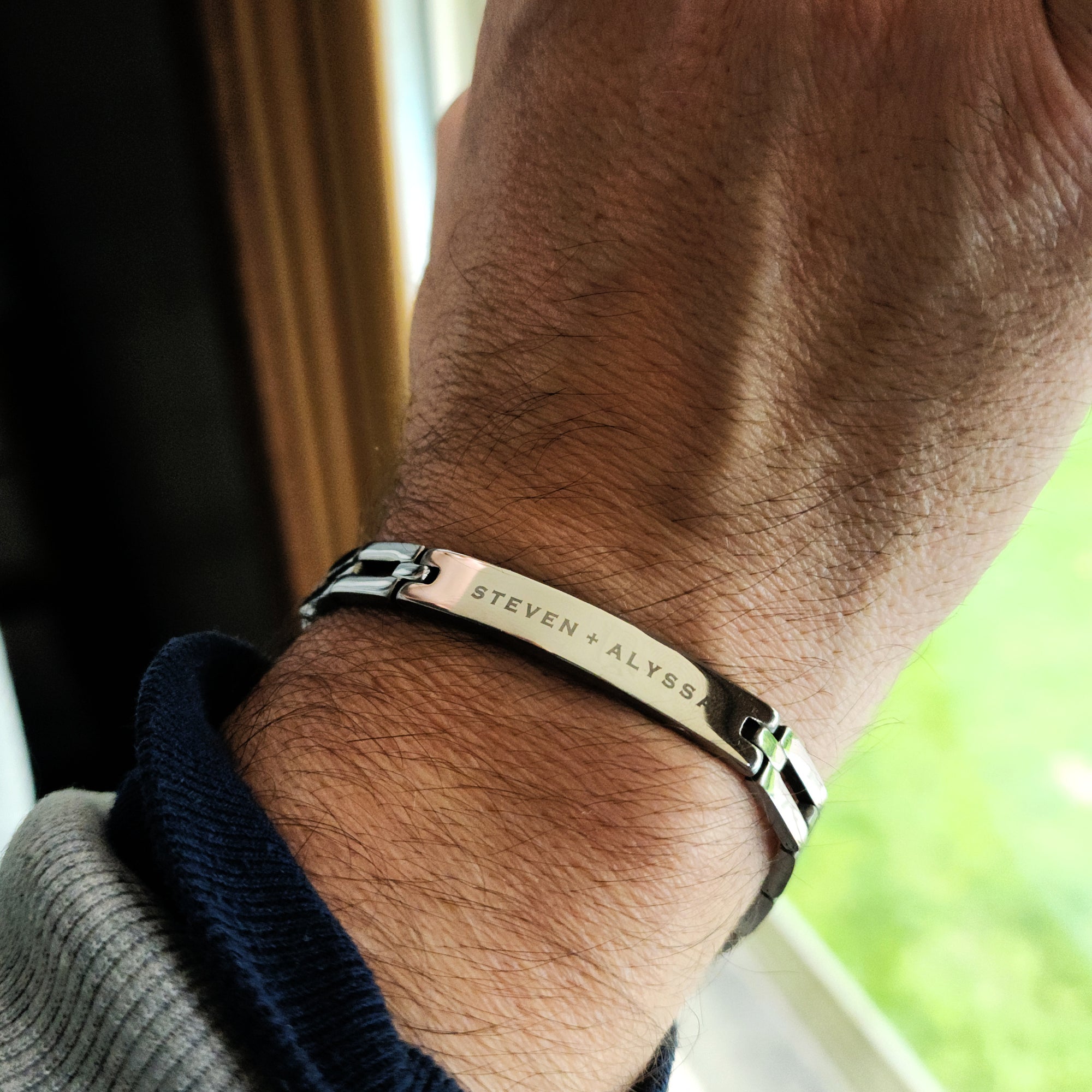 Bracelet with engraved names on a wrist, blurred background