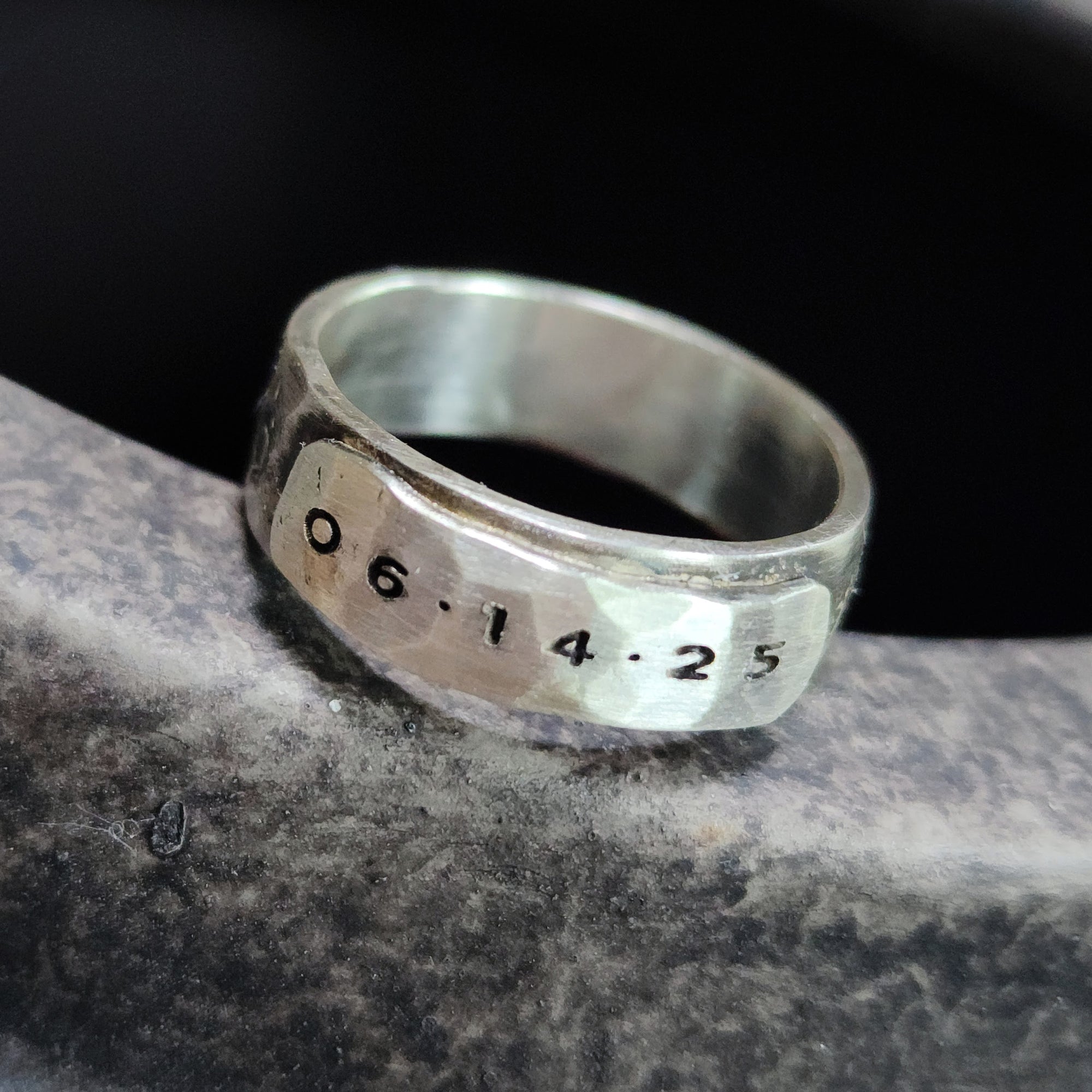 Silver ring with engraved date on a dark background