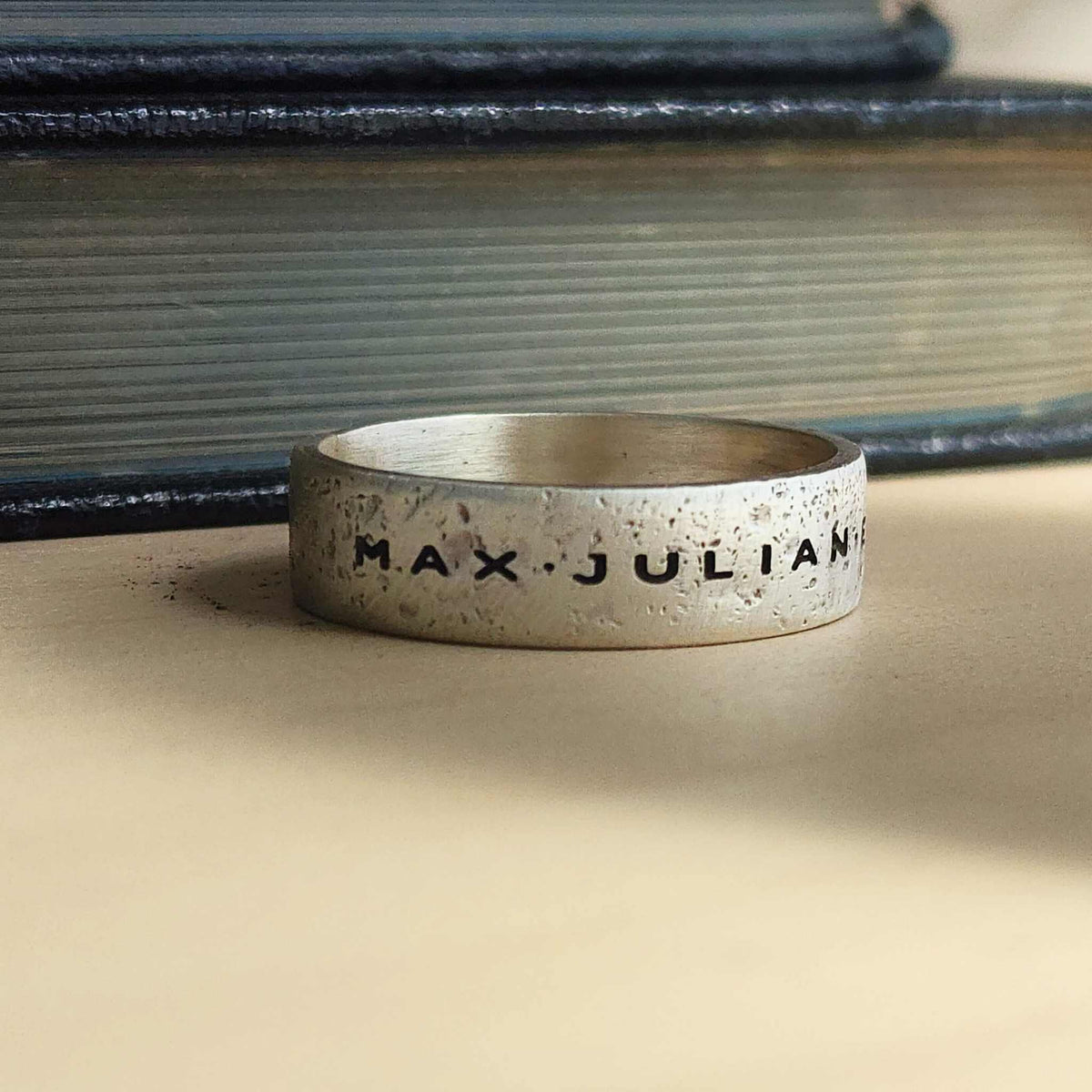 Men’s sterling silver name ring with rugged sandcast texture and oxidized finish, engraved band
