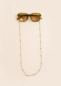 Sunglasses with a beaded chain on a beige background