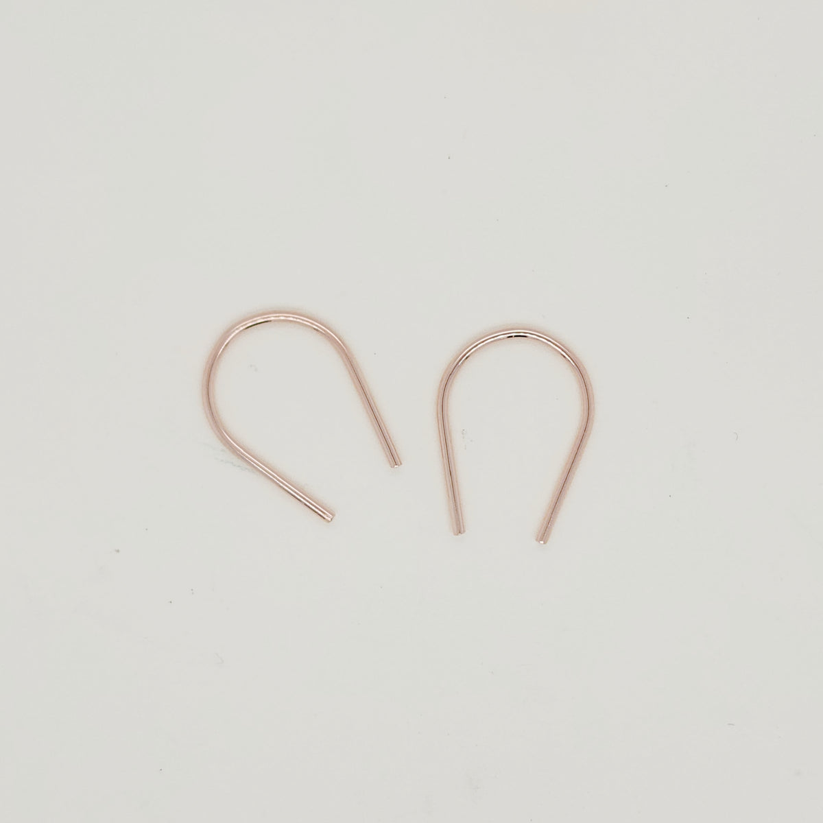 Minimalist gold U-shaped earring pair displayed on white background