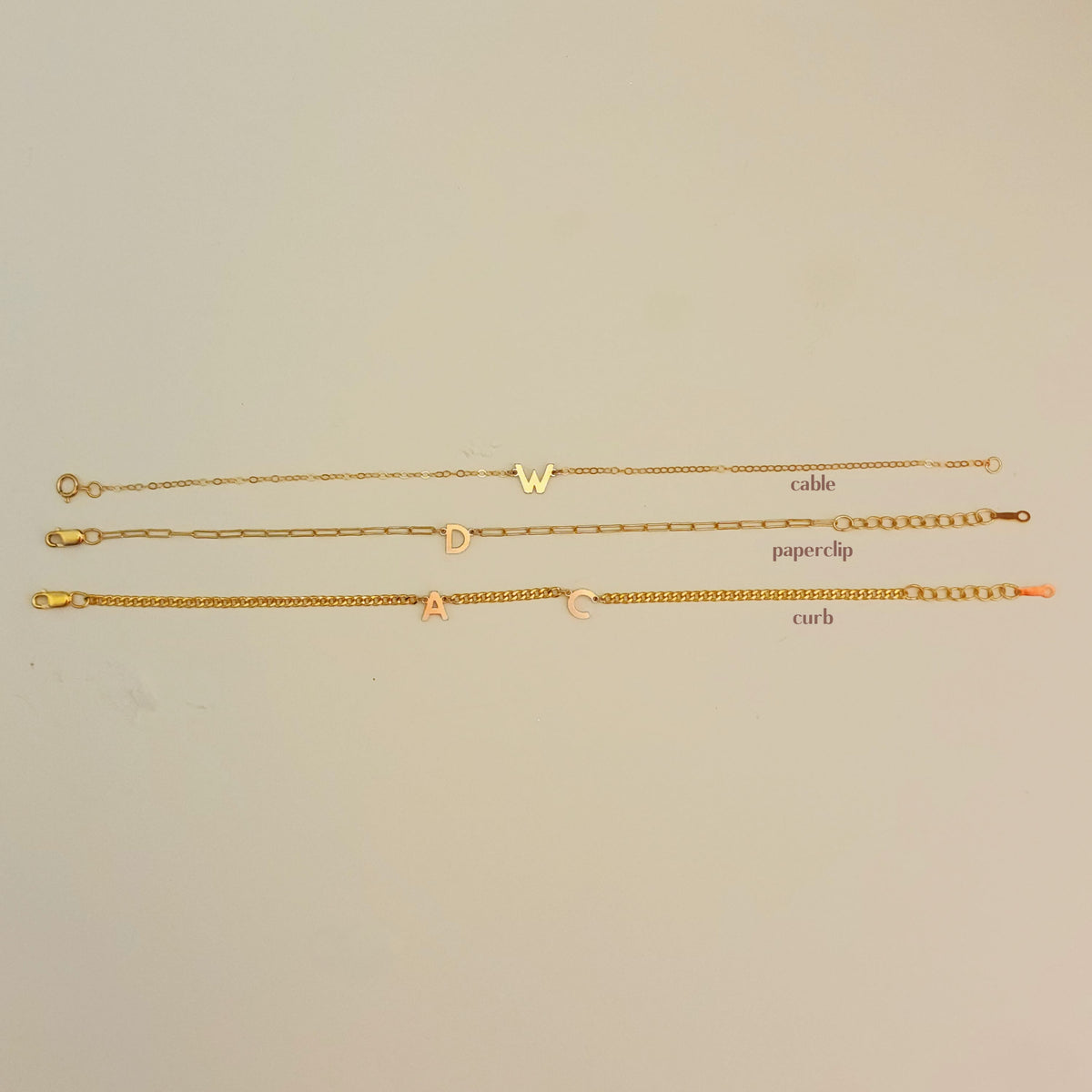 Three gold chains labeled 'cable', 'paperclip', and 'curb' on a beige background