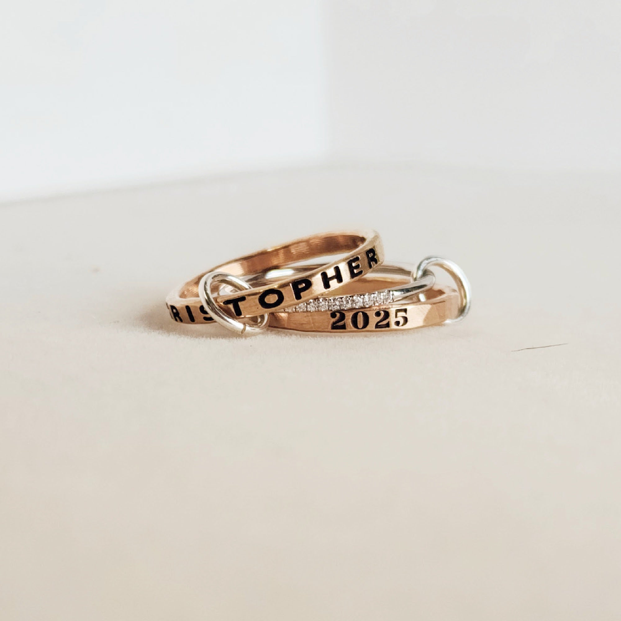 Two rose gold rings with engraved text on a light background