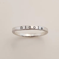 A gold-colored ring with the name 'nicole' engraved in a typewriter-style font.