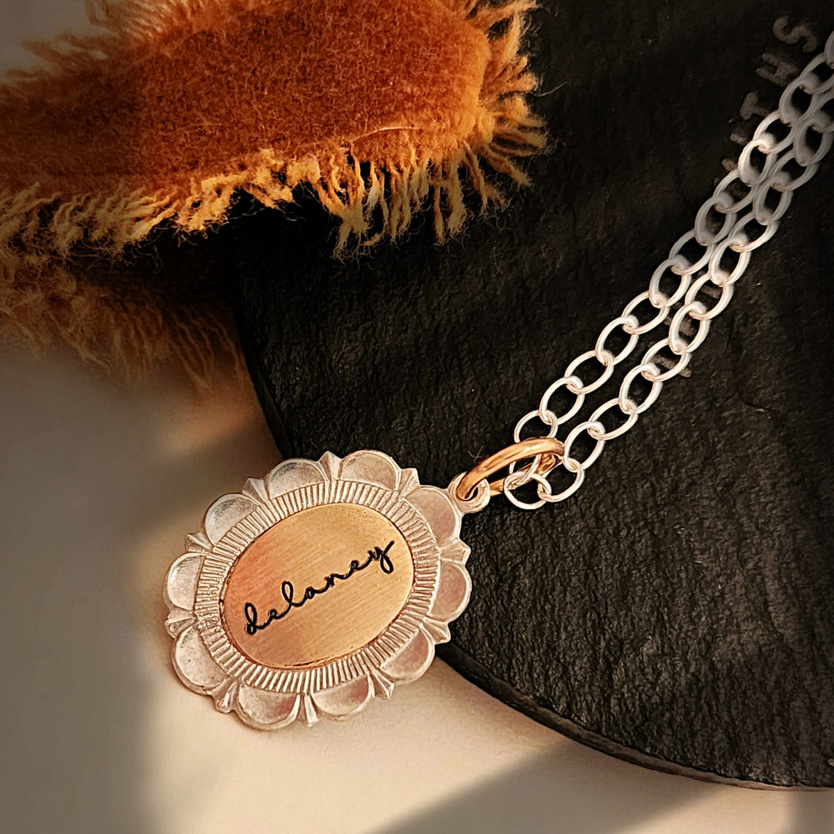 Necklace with a pendant that reads 'balance' on a textured surface.