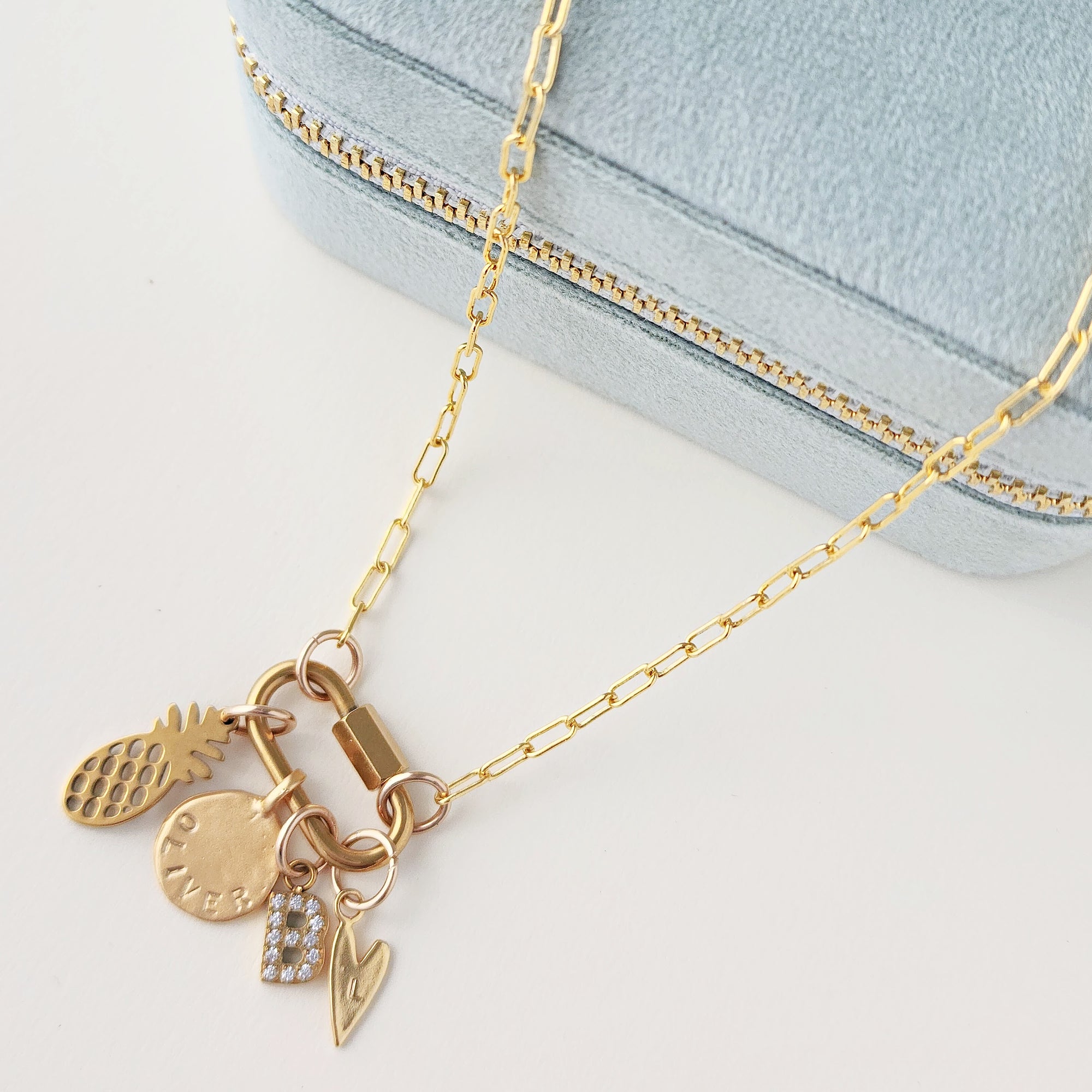 Gold necklace with charms on a light blue background