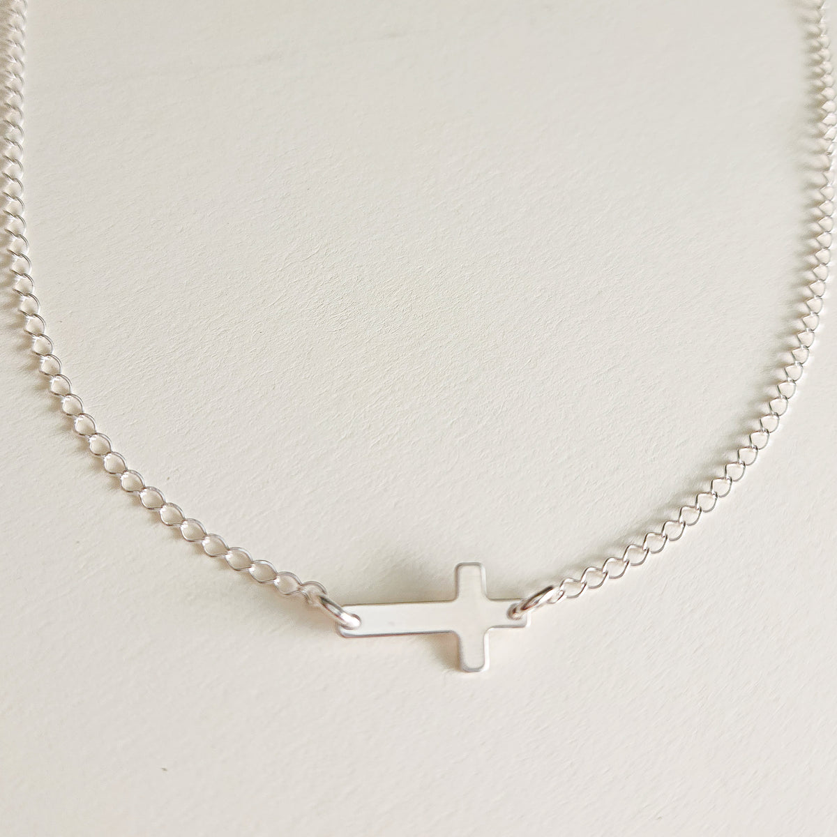 Sterling silver personalized cross necklace with blank engraving space on white background