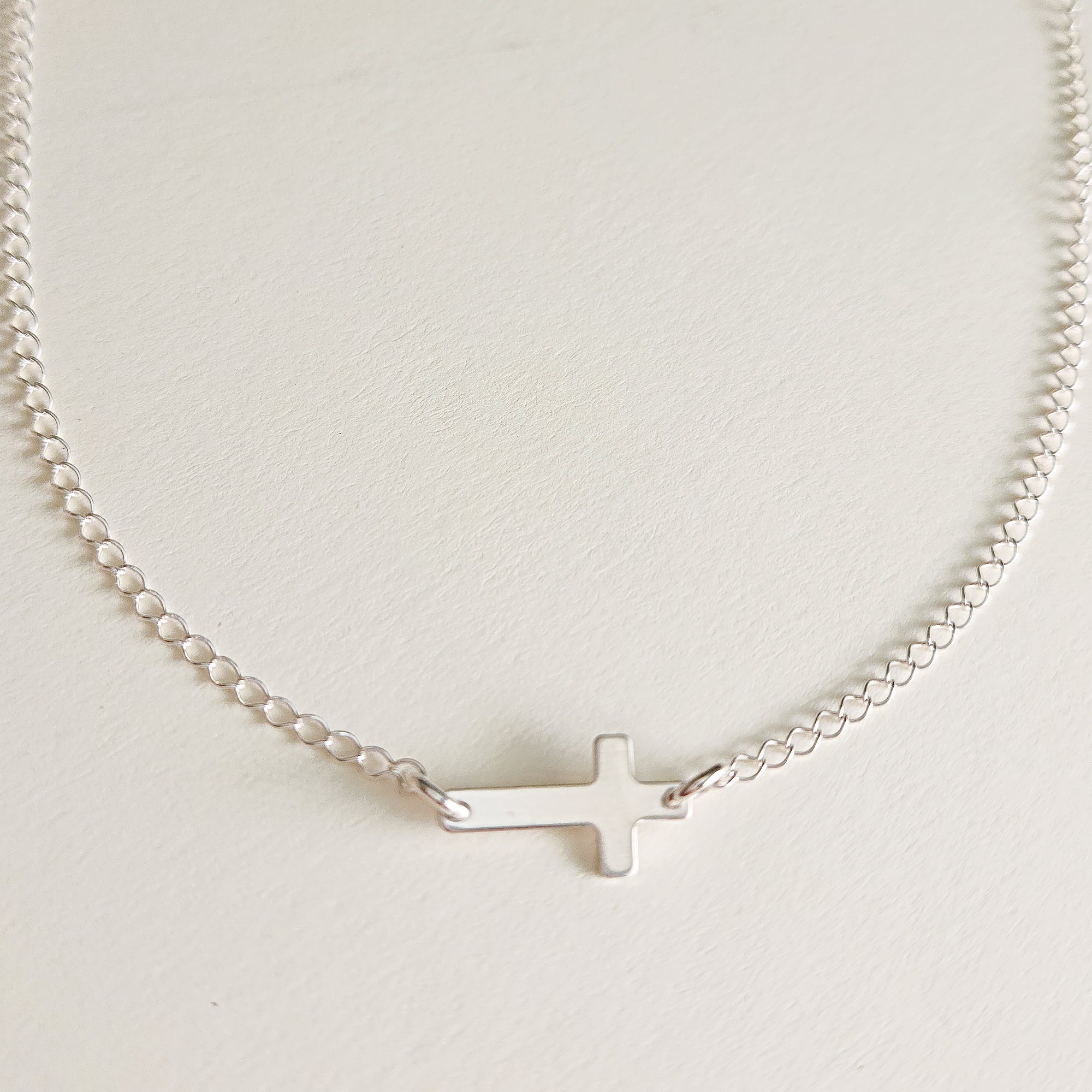 Sterling silver personalized cross necklace with blank engraving space on white background