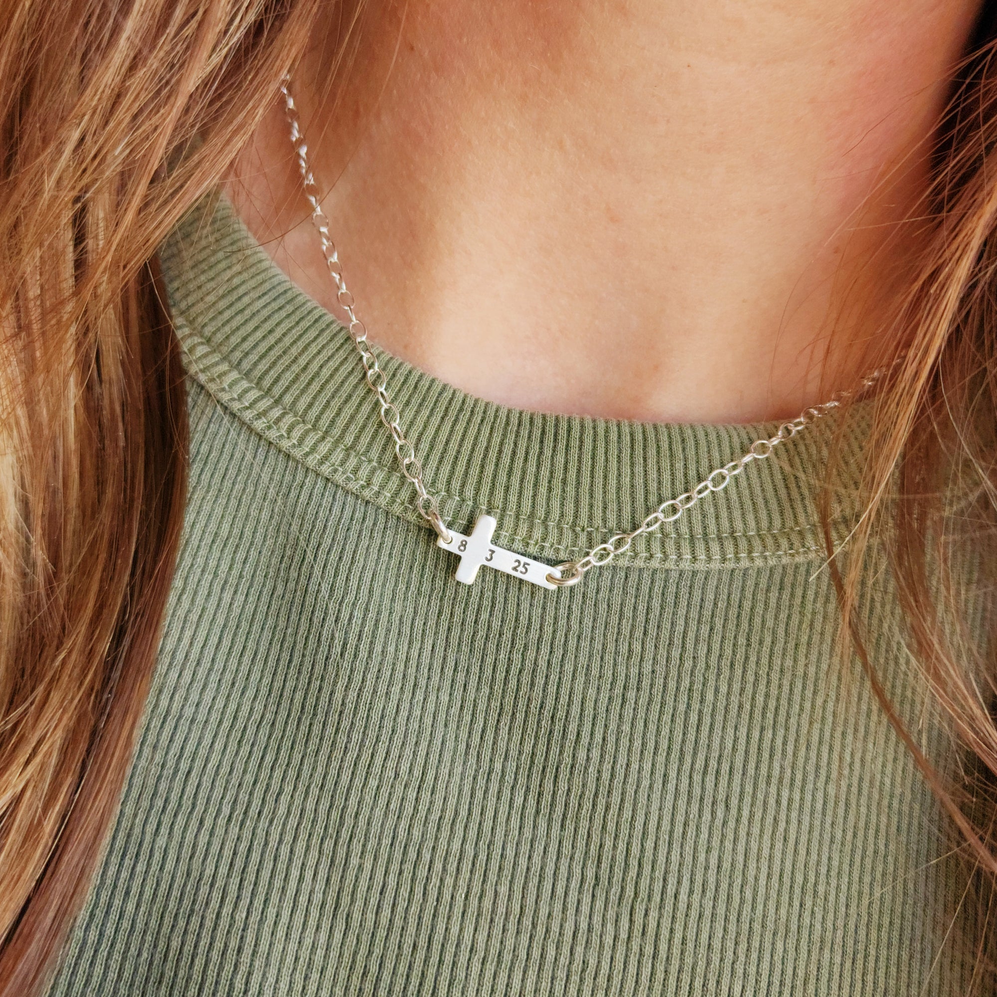 Sterling silver personalized cross necklace engraved with date 8 3 25 on a model’s neck