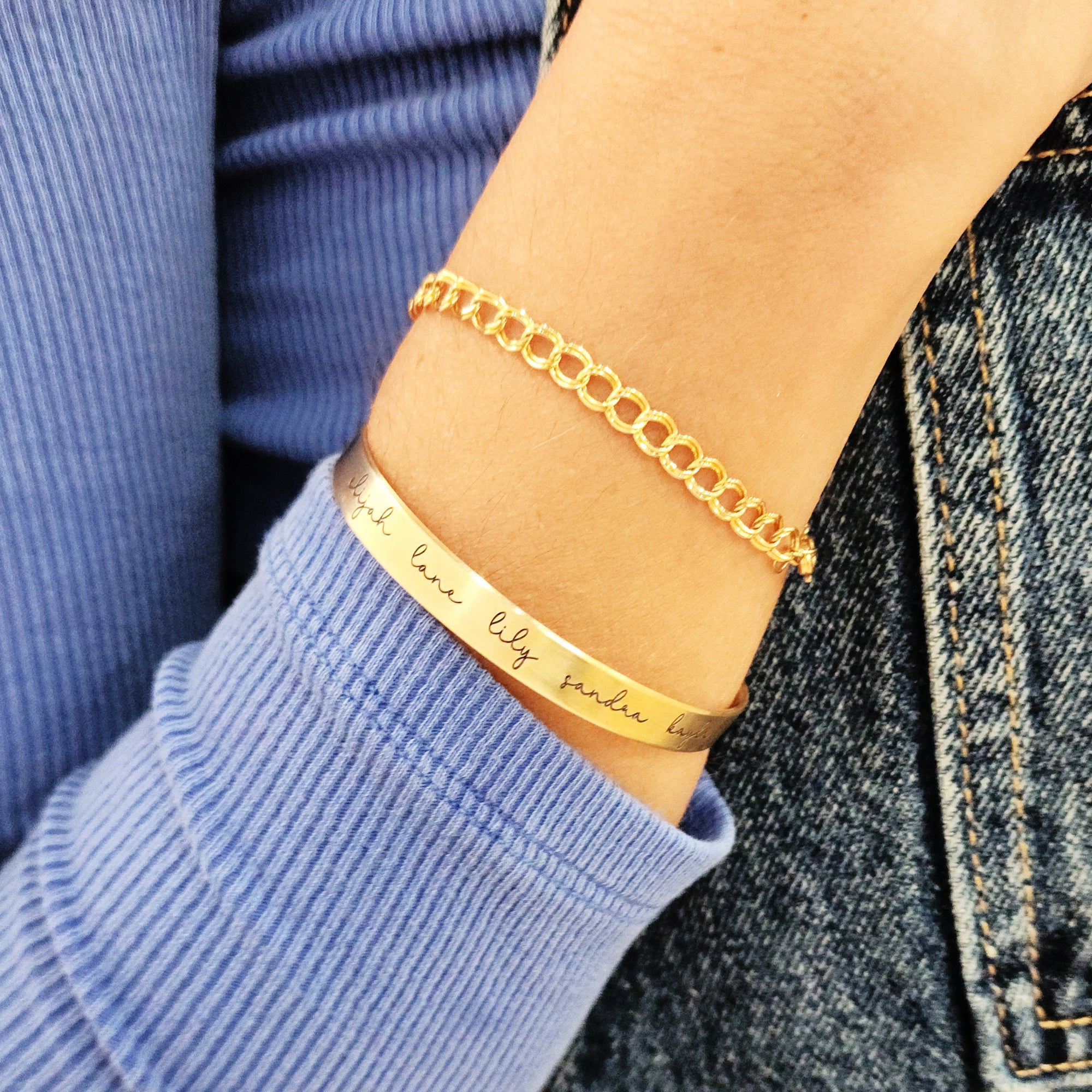 A gold-colored cuff bracelet with custom names engraved on it