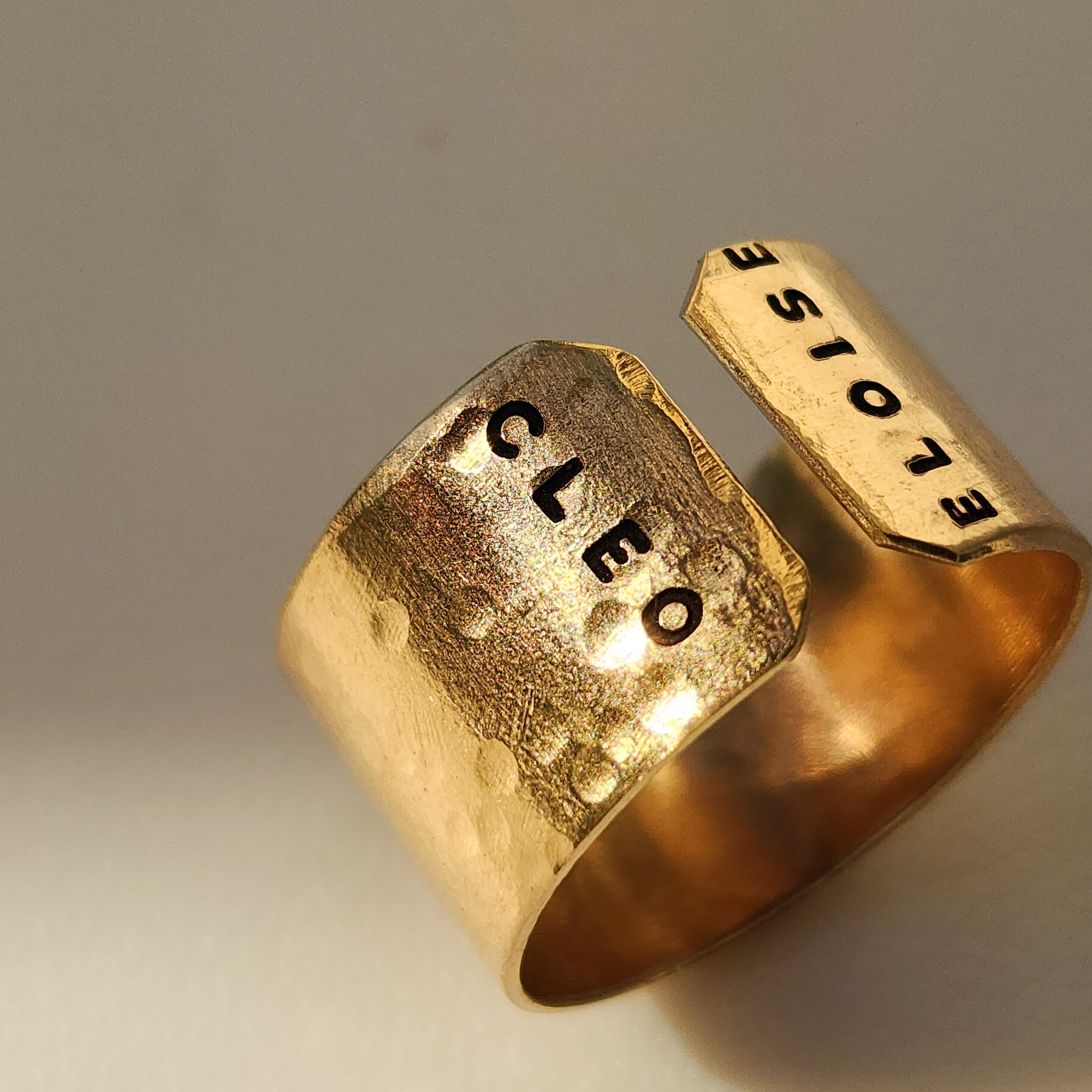 Close-up of personalized gold name cuff ring hand-stamped with Cleo and Eloise