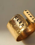 Close-up of personalized gold name cuff ring hand-stamped with Cleo and Eloise