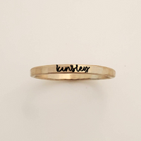 Gold ring with 'kensley' engraved on a beige background