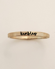 Gold ring with 'kensley' engraved on a beige background
