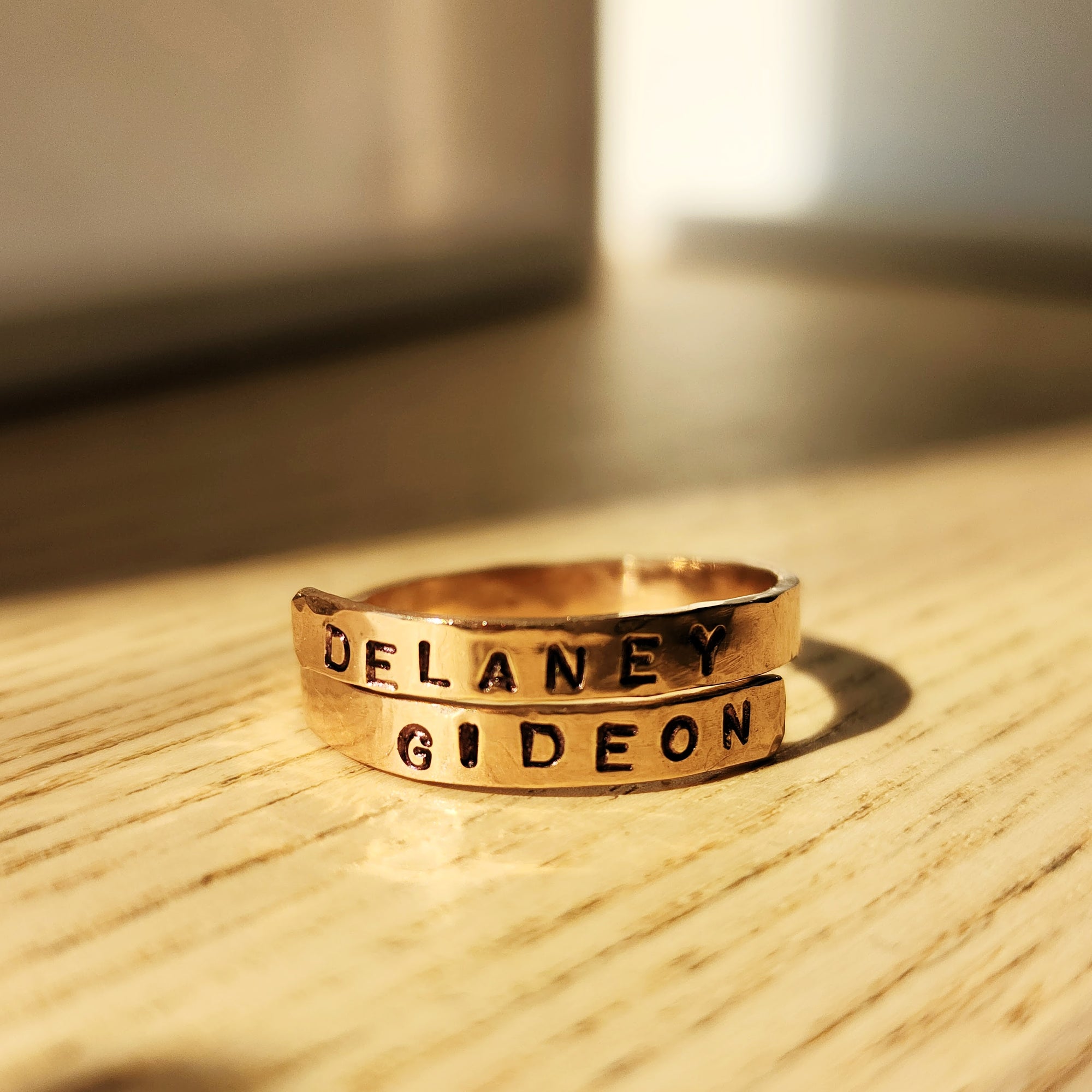 Personalized gold name wrap ring hand-stamped with Delaney and Gideon