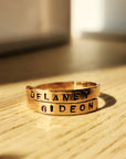 Personalized gold name wrap ring hand-stamped with Delaney and Gideon