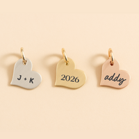 Three heart-shaped gold pendants with engraved text on a beige background