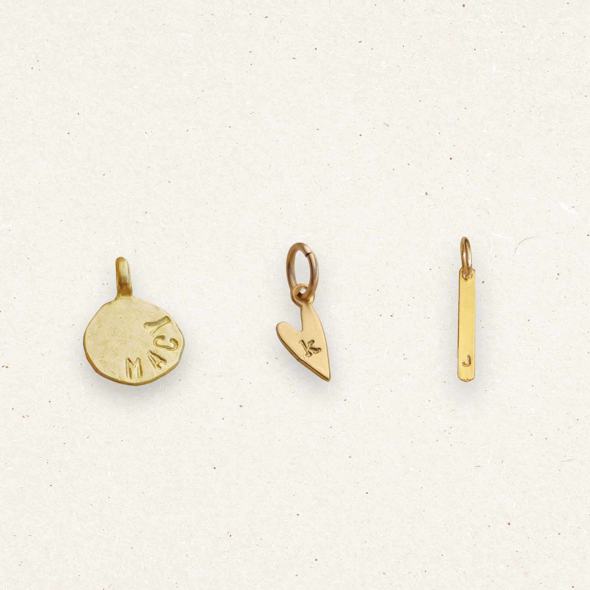 Three gold pendants on a light beige background