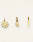 Three gold pendants on a light beige background