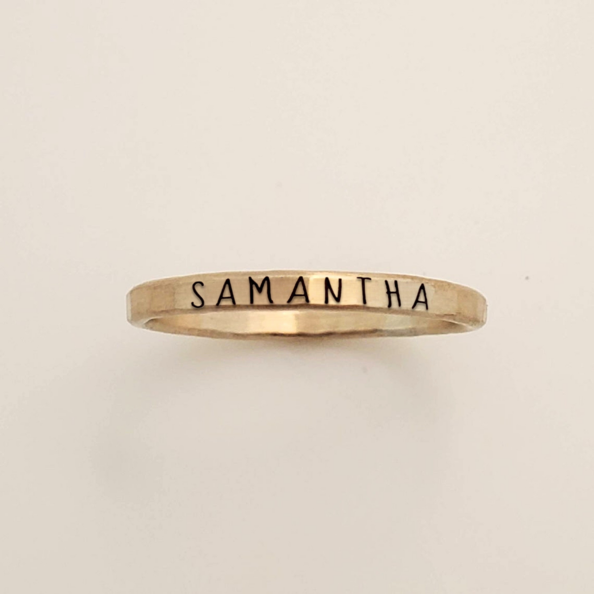 Gold ring with 'Samantha' engraved on a beige background