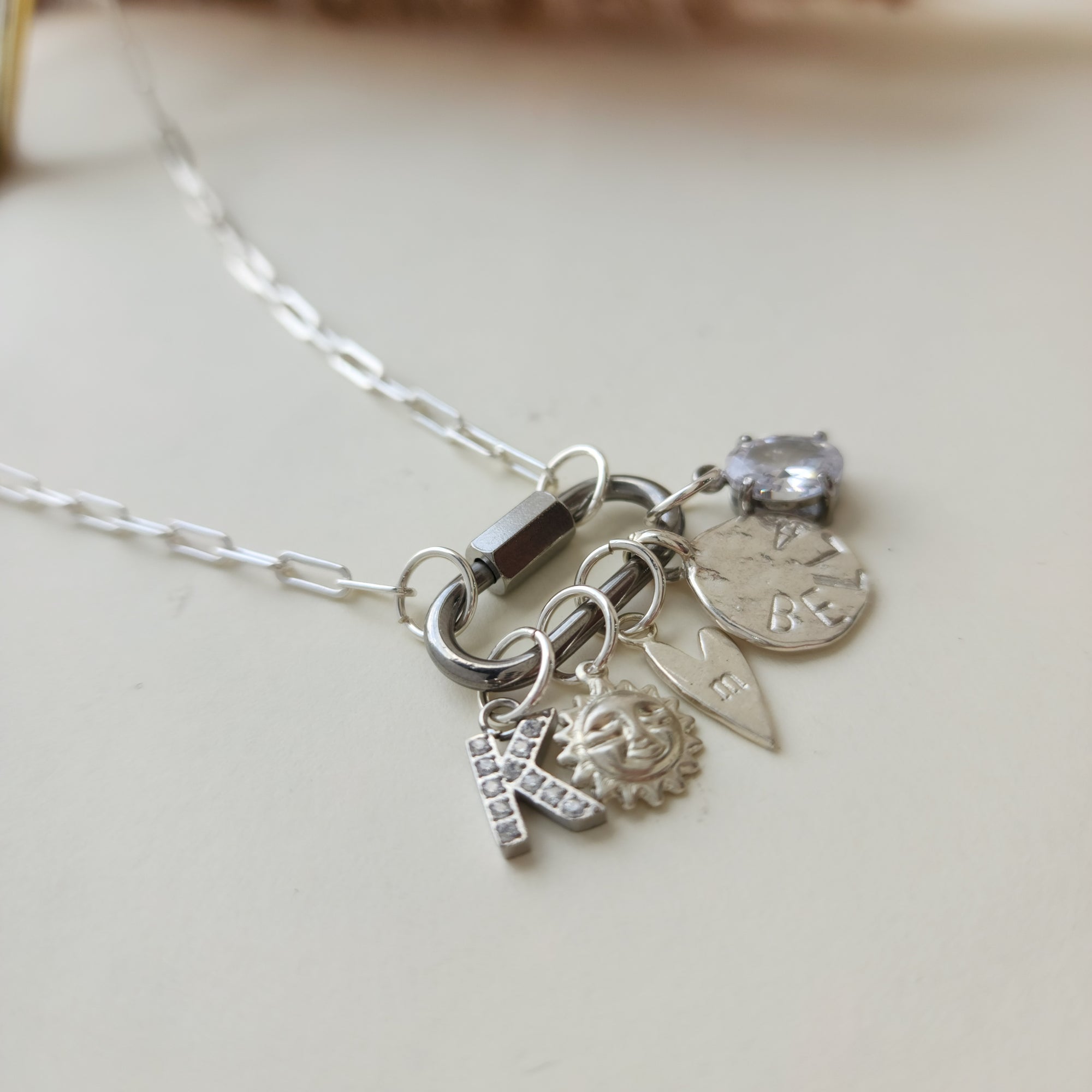 Silver necklace with various charms on a light background